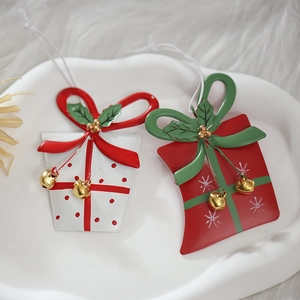 Set of two metal Christmas ornaments featuring a white gift box and red gift bag design