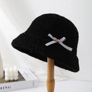 Detail of black faux shearling bucket hat with striped bow and metal emblem