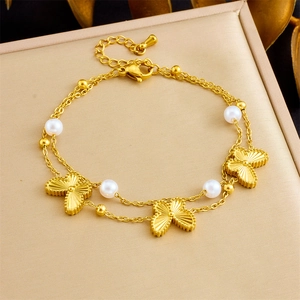 Dettaglio del bracciale a doppio strato dorato con farfalle e perle su porta gioielli