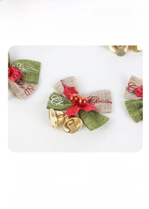 Detail of Christmas bow with green linen, red berries, and small golden bells