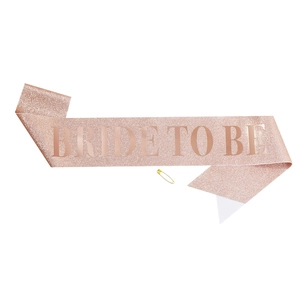 Detail of rose gold glitter sash with Bride To Be lettering and gold safety pin