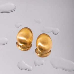 Minimalist 18k gold plated brushed stainless steel oval stud earrings on water droplets