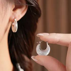 Eleganti orecchini a cerchio a forma di U in madreperla indossati da una modella in primo piano