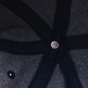 Detail of reinforced inner seams and metal rivet on a washed denim baseball cap