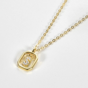 Detailed close-up of a golden S-letter pendant with crystals on a white background