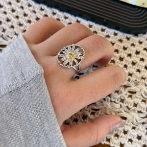 Elegant silver daisy flower ring with golden center and clear zircon on a lace background