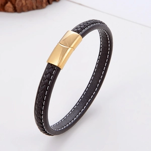 Macro view of black braided leather bracelet with gold magnetic clasp and white stitching