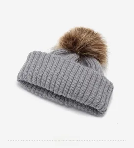 Close-up of gray knit beanie interior structure with premium fluffy brown faux fur pom