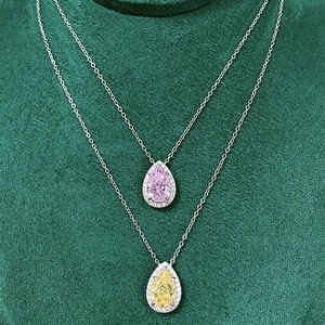 Detailed view of teardrop halo pendants with pink and yellow stones on green velvet