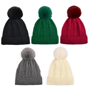 Detailed cable knit patterns on colorful winter beanies with soft faux fur pom-poms