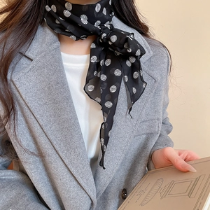 Close-up of elegant black polka dot silk scarf necklace layered with a grey wool blazer