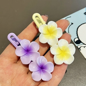 Close-up of purple and yellow gradient frangipani flower hair clips for girls