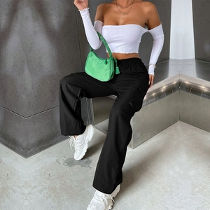 Détail d'un pantalon cargo noir à taille haute et d'un haut court blanc à épaules nues