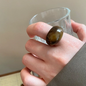 Macro view of a brown resin oval ring featuring vintage amber texture on a finger