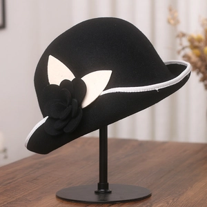 Detail of wool cloche hat featuring black camellia floral decor and white trim edges