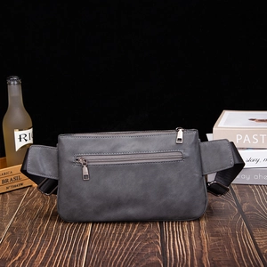 Detail of matte gray leather sling bag featuring silver metal zippers and nylon strap