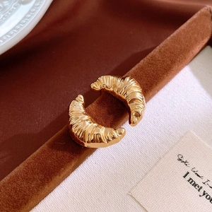 Detail of gold croissant hoop earrings with spiral texture on a velvet stand