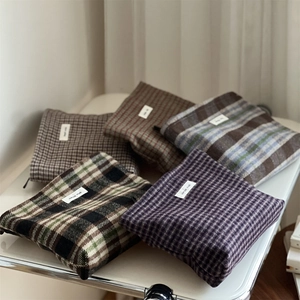 Set of retro plaid wool makeup bags in various colors on a white pedestal display