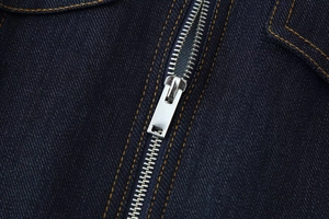 Détail de la fermeture éclair en métal et coutures contrastées sur denim bleu foncé