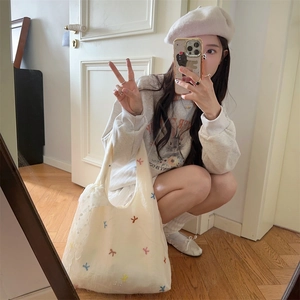 Mirror selfie showing the off-white mesh tote bag with colorful bow embroidery details