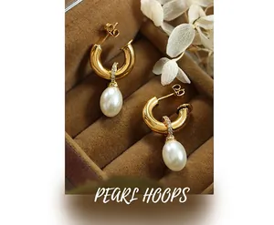 Close-up of gold C-shape earrings with white pearls and small zircon stones in a box