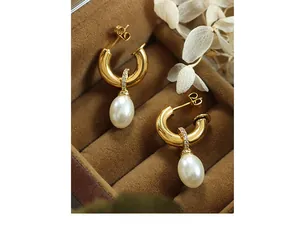 Close-up of gold C-shape earrings with white pearls and small zircon stones in a box