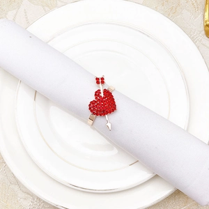 Detail of rose gold heart napkin ring with red rhinestones on a white linen napkin