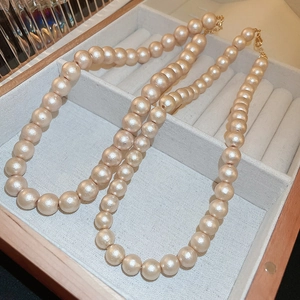 Collana di perle barocche champagne con chiusura dorata in una scatola beige
