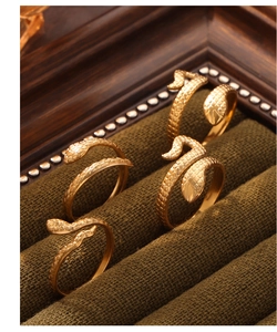 Detailed view of gold-plated snake rings with scale texture on green velvet