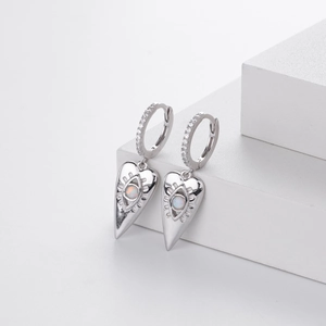 Detail of silver heart earrings featuring opal stone and devil eye with zircon pavé
