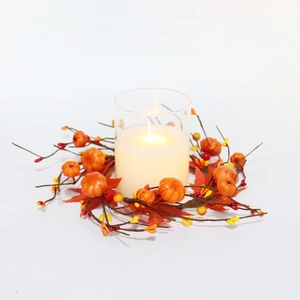 Fall wreath with pumpkins, maple leaves, and a glass candle holder on a white background