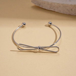 Close-up of silver-tone polished bow cuff bracelet with adjustable bead-end design