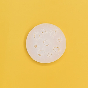 White multi-hole lotus root shaped silicone donut mold on bright yellow background