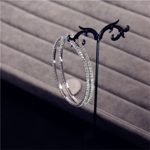 Detailed view of oversized silver crystal hoop earrings displayed on a black stand