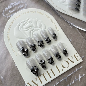 Detail of grey gradient press-on nails with 3D black rhinestones on a decorative card