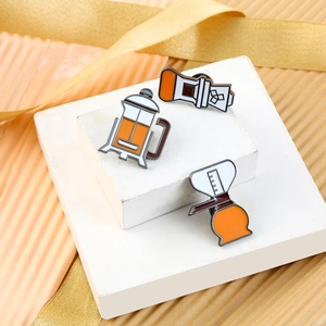 Macro shot of detailed enamel pins featuring coffee equipment in warm orange and brown