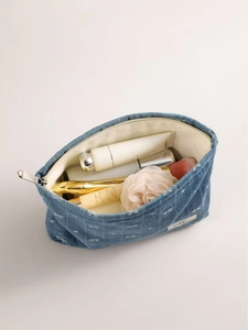 Denim makeup bag with white bow embroidery and spacious interior for toiletries