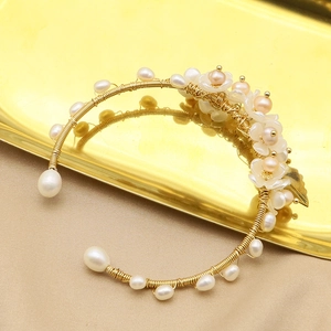 Handmade pearl bangle featuring gold wire wrapping and floral shell petals on silk