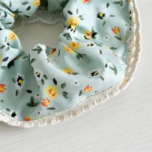 Close-up of floral mint green fabric hair scrunchie with delicate lace trim details