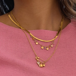 Close-up of layered gold paperclip necklaces with heart, lock, and key charms on a pink sweater