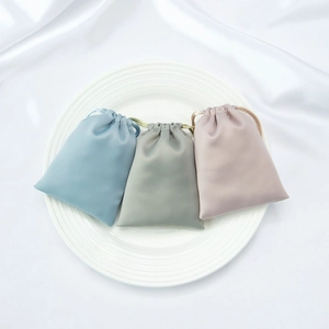 Detailed close-up of blue, grey, and pink satin drawstring pouches on a ceramic plate