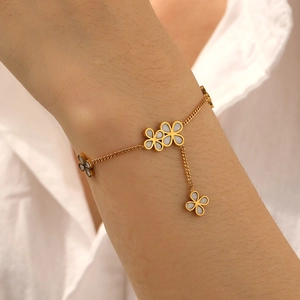 Gold-plated stainless steel chain bracelet with white shell flower charms on wrist