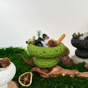 Green essential oil diffuser stone bowl with pine cones and cinnamon for home decor