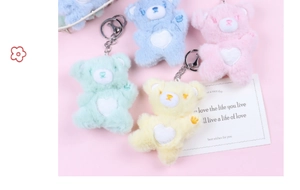 Close-up of colorful plush bear keychains with metal rings on pink background