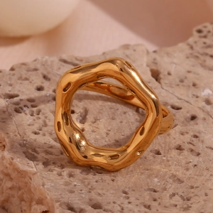 Macro shot of 18K gold plated irregular wave ring on natural stone showing fluid metal texture