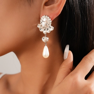 Close-up of Baroque silver-tone earrings with sparkling crystals and a waterdrop pearl