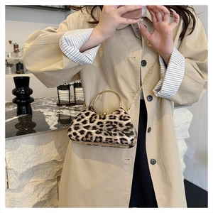 Detail of leopard print clutch with golden circular metal handle and thin chain strap