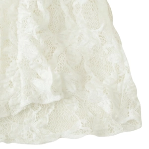 Close-up of white lace knit top featuring delicate floral patterns and intricate textures