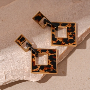 Detailed close-up of retro geometric leopard print earrings with gold metal frames