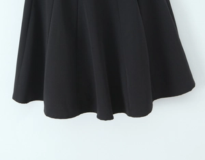 Dettaglio del mini abito nero stile Hepburn con orlo drappeggiato e tessuto liscio